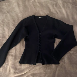 Mörkblå kofta från Gina Tricot XS - Supersnygg mörkblå kofta från Gina Tricot. Koftan har v-ringning, långa ärmar och knappar framtill i samma färg som tyget. Perfekt att styla med jeans för en clean look😚