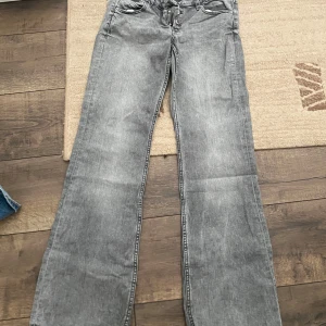 Grå bootcut jeans från Gina Tricot - Säljer ett par grå jeans från Gina Tricot i bootcut-modell. Jeansen har låg midja och en 3 knapps modell i midjan. Färg är grå byxorna är använd ett fåtal gånger och köpta för ett år sen. Pris går att diskutera 