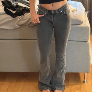 Grå bootcut jeans med låg midja - Säljer ett par grå jeans med bootcut-modell och låg midja. Jeansen har klassisk femficksdesign, dragkedja och knapp framtill. Snygg tvätt och skön passform, perfekta till sneakers eller boots.