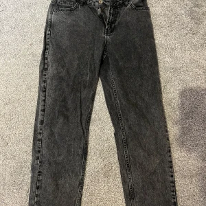 Svarta straight jeans i tvättad look - Säljer ett par svarta jeans med tvättad finish och klassisk femficksdesign. Jeansen har rak passform och normal midja, perfekta till sneakers eller boots. Materialet är robust denim som håller länge och ger en cool vintagekänsla.
