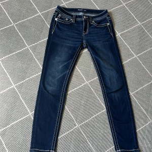 Mörkblå Miss Me jeans med broderade fickor - Hej! Säljer nu ett par snygga mörkblå jeans från Miss Me med kontrastsömmar och detaljerade bakfickor med broderi och paljetter. Modellen är skinny med låg midja och stretchigt jeanstyg som sitter tajt. Jeansen är knappt använda och är som i nytt skick!