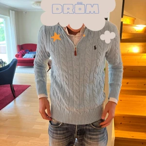 Ljusblå kabelstickad tröja Polo Ralph Lauren - Säljer en ljusblå kabelstickad tröja från Polo Ralph Lauren med half zip och klassisk broderad logga på bröstet. Tröjan har lång ärm, ribbade muddar och hög krage. Perfekt för lager-på-lager och snygg till jeans.