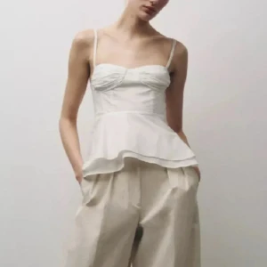 Vit peplum korsett-topp med smala band - Superfin vit korsett-topp med peplumvolang och smala axelband. Toppen har lätt rynkade kupor och markerad midja som ger en snygg siluett. Perfekt till sommarens alla outfits och lätt att matcha med både kjol och byxor. 2 SISTA ÄR LÅNDADE BILDER