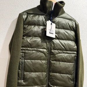 Grön Cardigan från Moncler - Snygg grön quiltad jacka från Moncler med stickade ärmar och dragkedja i rött, vitt och blått. Perfekt för kyliga dagar med sin kombination av stil och funktionalitet.