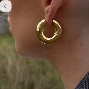 Chunky guldörhängen från Safira - Säljer ett par chunky, runda örhängen i guld från Safira. De är tjocka hoops med en riktigt snygg och modern look, perfekta för att lyfta vilken outfit som helst. Örhängena är blanka och har en enkel men statement-form som verkligen syns.