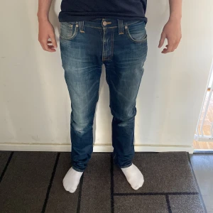 Nudie Jeans Thin Finn Greentone - Snygga blå jeans från Nudie Jeans, modell Thin Finn Greentone. Klassisk femficksdesign med orange sömmar och Nudie-logga på bakfickan. Jeansen har en smal passform och är tillverkade i mjukt bomullsjeansmaterial. Det är bara att höra av sig vid frågor och funderingar 😁