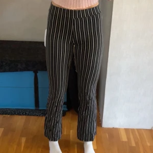 Svarta randiga byxor Gina Tricot XS - Snygga svarta byxor med vita vertikala ränder från Gina Tricot. Byxorna är korta på mig (jag är 170cm) men bör passa någon som är lite kortare, runt 160-165cm. De är utsvängda i benen. Tillverkade av 97% viskos och 3% elastan, de är mjuka och stretchiga.💕 