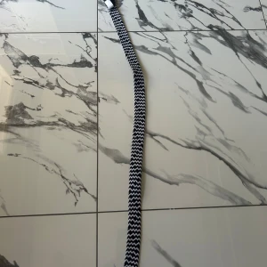 Svartvitt flätat bälte från LJL - Snyggt svartvitt bälte från LJL med flätad design. Bältet är gjort av polyester och elastan, med svarta skinn-detaljer vid ändarna. Perfekt accessoar för att lyfta din outfit med en cool kontrast och mönstrad look.