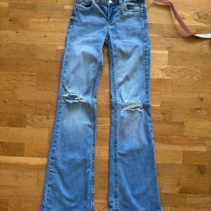 Bootcut jeans med slitningar från Nelly i storlek 32 - Nelly jeans i storlek 32, använda fåtal gånger. Lite slitet i benslut på ena benet. 