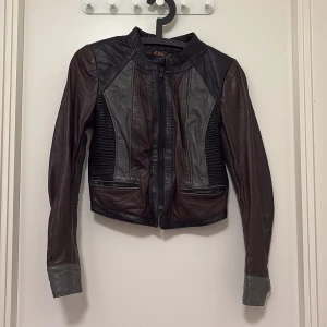Cool skinnjacka från InWear, strl 36 - Säljer en snygg skinnjacka från InWear i mörkbrunt och svart med grå detaljer. Jackan har dragkedja framtill, ribbade partier på sidor och ärmar samt coola detaljer vid ärmslut. Perfekt för dig som vill ha en edgy look. Priset kan diskuteras 