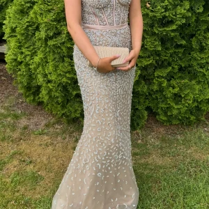 Champagnefärgad långklänning med paljetter och volang - Säljer en magisk champagnefärgad långklänning med glittriga paljetter och vackra volangdetaljer. Klänningen har ärmlös design, markerad midja och transparenta partier upptill. Perfekt för bal eller fest! 💫