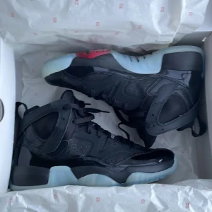 Svarta Nike Air Jordans med isblå sula - Säljer ett par svarta Nike Air Jordans med glansiga detaljer och isblå genomskinlig sula. Skorna har snörning, rund tå och röd Jumpman-logga på plösen. Perfekta för dig som gillar streetwear och vill sticka ut med en unik sneaker. KVITTO FINNS DOM ÄR RIKTIGA