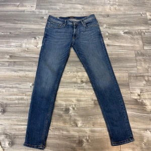 Blå skinny jeans Liam - Säljer ett par klassiska blå skinny jeans i modellen Liam. Jeansen har fem fickor, normal midja och snygga kontrastsömmar. Perfekta för dig som gillar en smal passform och tidlös stil.