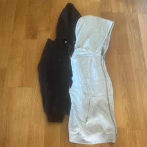 Två hoodies med dragkedja - Säljer två hoodies, en svart och en ljusgrå. Båda har huva med dragsko och dragkedja framtill. Perfekta för lager-på-lager och chill dagar. Klassisk passform och mjukt material. Säljer även dessa var för sig, men köp båda för bara 250 kr. 