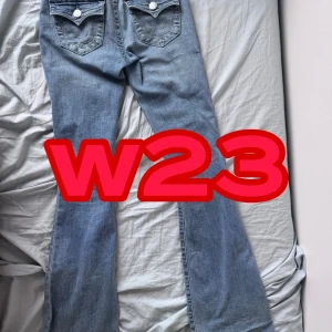 True religion - Säljer ett par ljusblå jeans från True Religion, modell Becca Mid Rise Bootcut. Byxorna har snygga detaljerade bakfickor med lock och silverfärgade knappar samt klassisk True Religion-patch bak. Bootcut-modell med normal passform. w23 helt nya 