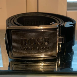 Svart skärp från Hugo Boss - Snyggt svart bälte från Hugo Boss med ett stilrent metallspänne. Den är 120 cm.