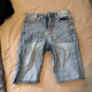 Ljusblå jeansshorts slim fit - Säljer ett par ljusblå jeansshorts från & Denim i slim fit-modell. Klassisk femficksdesign med råa kanter nertill och dragkedja. Perfekta för sommaren och enkel att matcha med t-shirt eller skjorta.