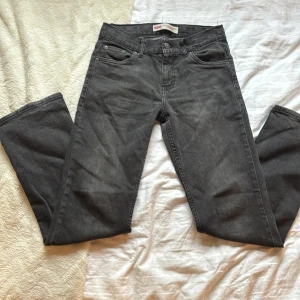 Gråa Levis jeans  - Säljer ett par klassiska gråa Levis jeans med raka ben och femficksmodell. Jeansen har tydlig Levis-lapp bak i midjan. Perfekta för dig som gillar en tidlös och avslappnad stil.