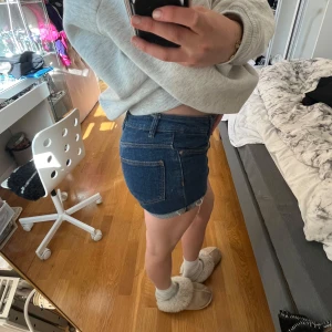 Blå jeansshorts från MNG - Säljer ett par klassiska blå jeansshorts från MNG med råa kanter och femficksmodell. Shortsen har normal passform och hög midja, perfekta för sommardagar. Snygga att matcha med en enkel topp eller hoodie.