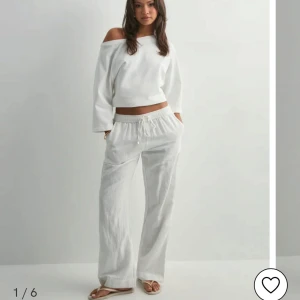 Vita linnebyxor med dragsko - Säljer ett par vita linnebyxor med avslappnad passform och dragsko i midjan. Byxorna har raka ben och sidfickor. Lätta och luftiga, passar grymt till sommaren. De är uppsydda så att de passar någon som är 163 cm perfekt!