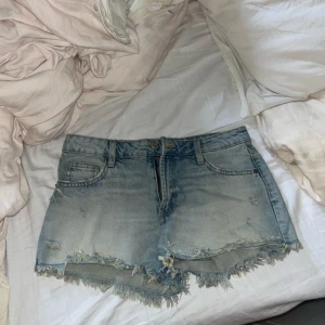 Ljusblå jeansshorts - Säljer ett par ljusblå jeansshorts. Shortsen har låg midja och en avslappnad passform, perfekta för varma dagar. 