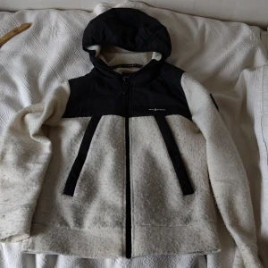 Vit och svart jacka med huva från Sail Racing - Säljer en snygg jacka från Sail Racing i vitt ull och svart polyester. Xs fast passar S bättre. Denna jack är väldigt rare eftersom den såldes ett kort tag bara. Priset var 2000 kr
