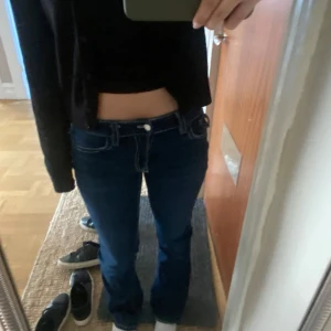 Lågmidjade Mörkblå bootcut jeans med vita sömmar - Säljer ett par mörkblå jeans med bootcut passform och tydliga vita kontrastsömmar. Byxorna har låg midja och fickor med lock och knapp bak. Skriv för frågor💕