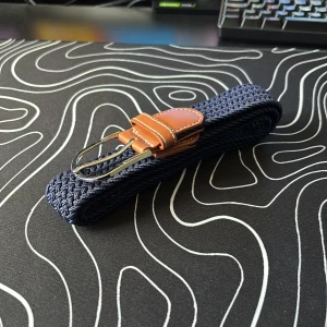 Blått flätat bälte med bruna skinn-detaljer - Snyggt blått flätat bälte med silverfärgat spänne och bruna skinn-detaljer vid spännet. Perfekt accessoar för att lyfta din outfit med en modern touch.