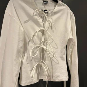 Vit långärmad tröja med snörning från Gina Tricot - Säljer en vit långärmad tröja från Gina Tricot med snygg snörningsdetalj framtill. 