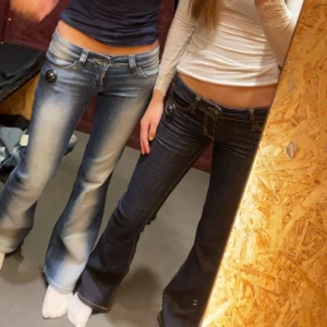 Mörkblå bootcut jeans med kontrastsömmar - Säljer ett par mörkblå bootcut jeans med snygga kontrastsömmar och klassiska fickor. Jeansen har låg midja och utsvängda ben, perfekt för en trendig look. Passar dig som gillar 00-talsstil.