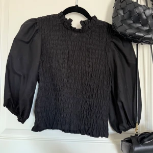 Svart blus med puffärmar - Säljer en svart blus från h&m med puffiga ärmar och smockad framsida. Storlek 36