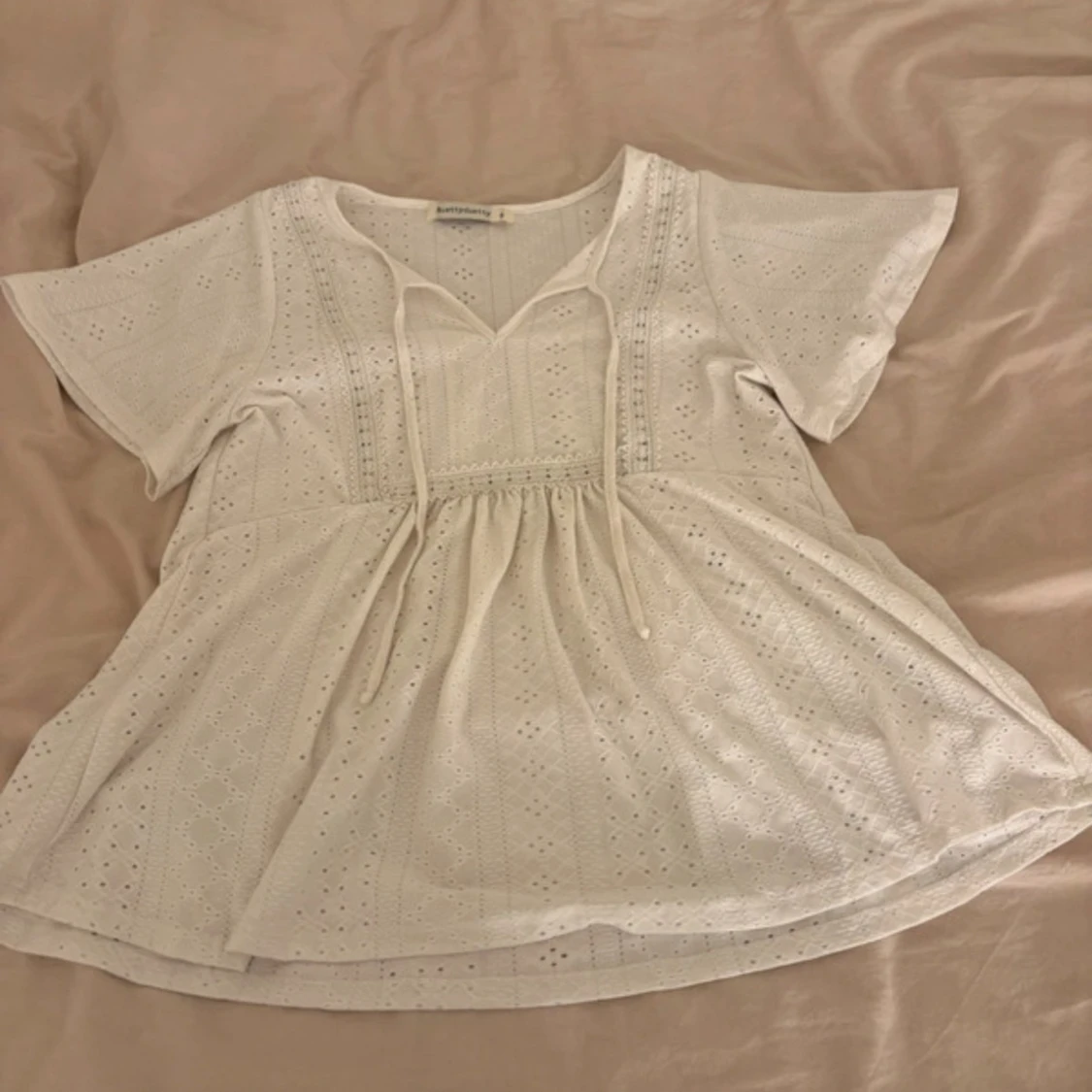 Vit blus med knyt och broderade detaljer