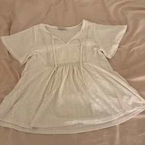 Vit blus med knyt och broderade detaljer - Vit blus i strl xs, minns inte var den är köpt ifrån! Använd ungefär 3 ggr, säljer för att den sitter för stort på mig!