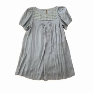 Ljusgrå kortklänning från Kookai - Supersöt ljusgrå klänning från Kookai med korta ärmar och paljetter. Klänningen har en lös passform och är tillverkad i ett mjukt, glansigt material. 