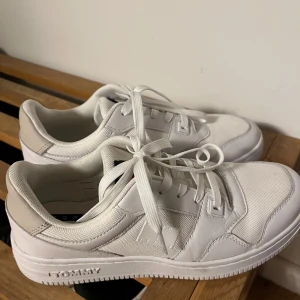 Vita sneakers från Tommy Hilfiger - Snygga helvita sneakers från Tommy Hilfiger med klassisk design och diskret logga på sidan. Skorna har snörning, rund tå och platt sula. Perfekta för en stilren och fräsch look.