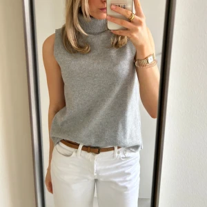 Grå ärmlös stickad väst med polokrage - Säljer en stilren grå stickad topp från Zara med hög ribbad polokrage. 