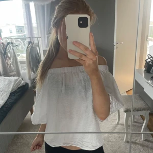 Vit offshoulder blus - Säljer en vit offshoulder blus med trekvartsärmar. Blusen har en lös passform och är tillverkad i ett lätt, strukturerat tyg. Perfekt för varmare dagar och enkel att styla med olika underdelar.