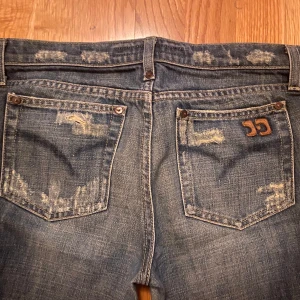 Blå jeans med slitningar - Snygga blå jeans med slitningar och en cool detalj på bakfickan. Har inga bilder på, säljer billigt för att bli av med de. 