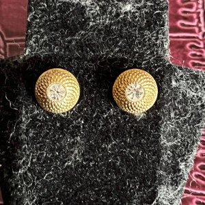 Guldörhängen med glittrande stenar - Snygga guldörhängen med en glittrande sten i mitten. De har en elegant, rund design med ett mönster som ger en lyxig känsla. Perfekta för att ge en touch av glamour till din stil.