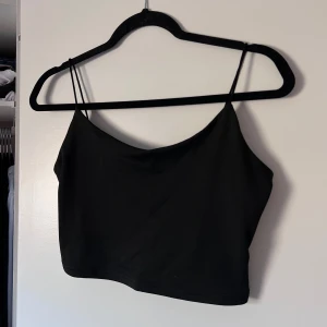Svart croppad linnetopp med låg rygg - Snygg svart croppad linnetopp med tunna axelband och låg rygg. Perfekt för varma dagar eller som ett lager under en jacka. Enkel och stilren design som passar till det mesta. Aldrig använd. Önskar du veta exakta mått? Tveka inte att höra av dig!