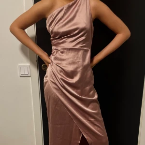 Balklänning från Moments S-Nyskick!  - En så fin klänning som tyvärr blev lite för stor och skickades aldrig tillbaka✨💕 Klänningen är i blankt gammelrosa lyxigt tyg med slits fram. Så fin i ryggen också✨Storleken är XS men som en S.  Dottern på bilden är 164 cm utan klack. 