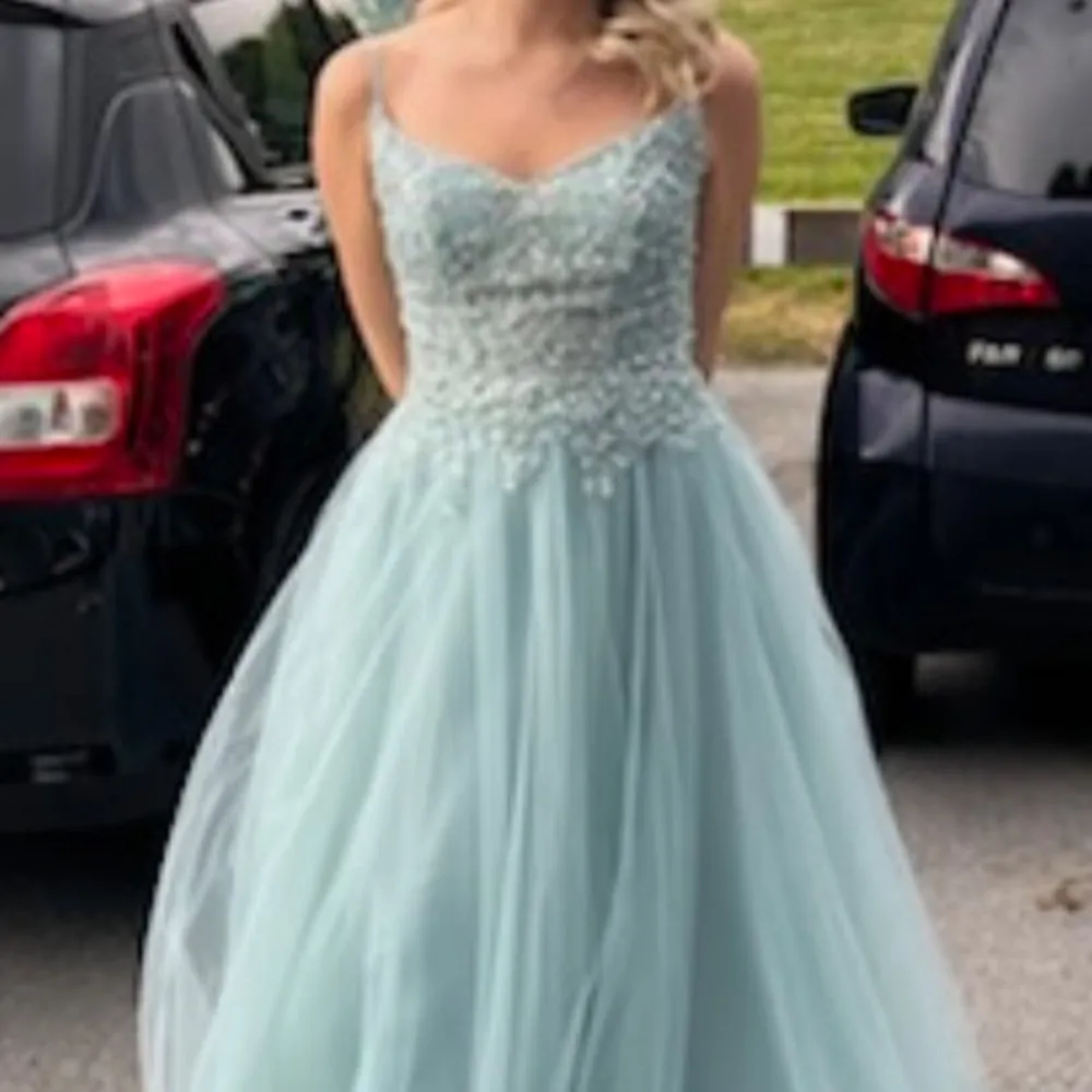 ljusblå långklänning med glittrande paljetter på överdelen. Klänningen har en v-ringad design vilket ger en stilren och festlig look. Perfekt för bal eller andra speciella tillfällen. Köpt för 1150kr. Mekot.