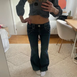 Lågmidjade utsvängda jeans med strass / nitar - Så coola lågmidjade utsvängda jeans med diamanter fram och på bakfickor! Har ett blekt streck se sista bild, fram och bak men syns inte mycket när man har på sig dem🥰