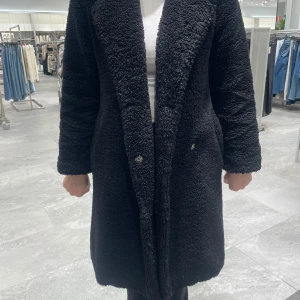 Svart teddyjacka - Säljer en mysig svart teddyjacka med långa ärmar och knappar framtill. Perfekt för kyliga dagar när du vill hålla dig varm och stilren. Jackan har en klassisk passform och är enkel att matcha med olika outfits. Från bikbok i xs.