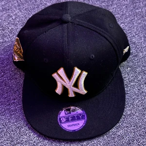 Svart new era keps.  - Snygg svart keps från New Era med broderad logga framtill. Kepsen har en justerbar snapback och är en del av 9FIFTY-serien. Perfekt för en sportig look.