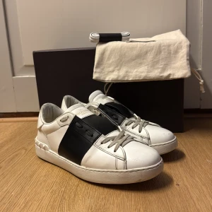 Valentino Open sneakers i vitt och svart - Säljer ett par snygga valentino open skor.  Passar väldigt bra nu till sommaren. Skicket är väldigt bra skulle  säga 7/10. Pga säljer skorna då jag har växt ur dom.                                                Det ingår dustbag, nya snören och original box.(allt är original)