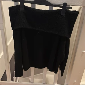 Svart offshoulder tröja - Snygg svart offshoulder tröja med långa ärmar. Perfekt för en stilren look. Tröjan har en bred kant upptill som ger en elegant touch.