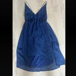 Blå klänning från Jeane Blush - Snygg blå klänning från Jeane Blush med smala axelband och v-ringning. Klänningen har en luftig passform och är perfekt för varma dagar. Den har en elegant öppen rygg🌸