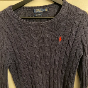 Mörkblå tröja från Ralph Lauren - Mörkblå kabelstickad tröja från Ralph Lauren i pima bomull med rött Ralph lauren märke på vänstra bröstet. 💕 
