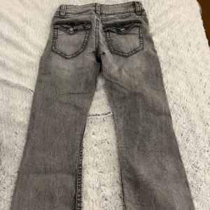 Grå jeansbyxor från Smartcoo - Snygga grå jeansbyxor från Smartcoo med en klassisk femficksdesign. Byxorna har en rak passform och är perfekta för en avslappnad stil. De har en dragkedja och knapp framtill för enkel stängning.